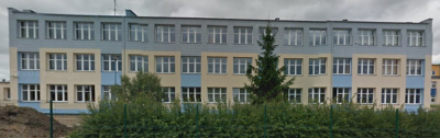 Współczesne zdjęcie. Przedstawia widok na prosty, horyzontalny budynek szkoły za ogrodzeniem. Jest to II Liceum Ogólnokształcące im. Jana III Sobieskiego w Tczewie. 