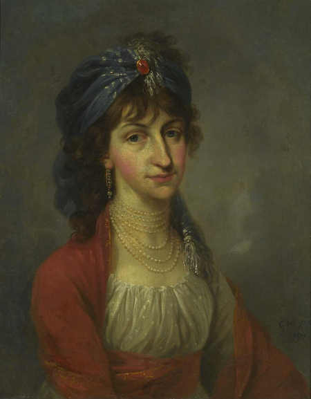 Portret kobiety w chuście na głowie. Kobieta ma szczupłą twarz i mocno zaróżowione policzki. Na szyi sznur pereł. Suknia jasno-czerwona. Jest to portret Kazimiery Wilżyny. 